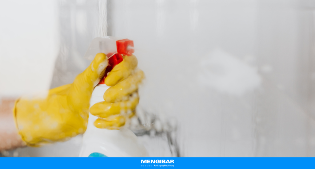 Household cleaning in action: yellow-gloved hand spraying cleaner on glass, illustrating efficient and modern cleaning practices.