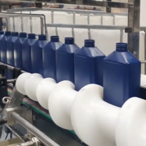 Image of the ATEX line for filling glass air freshener bottles, showing blue bottles aligned on a filling machine with corrosion protection system and special ventilation.