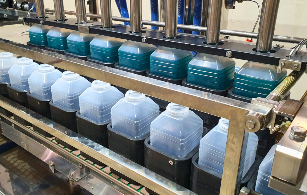 Automatic linear volumetric filling line with multi-head dosing system for square bottles